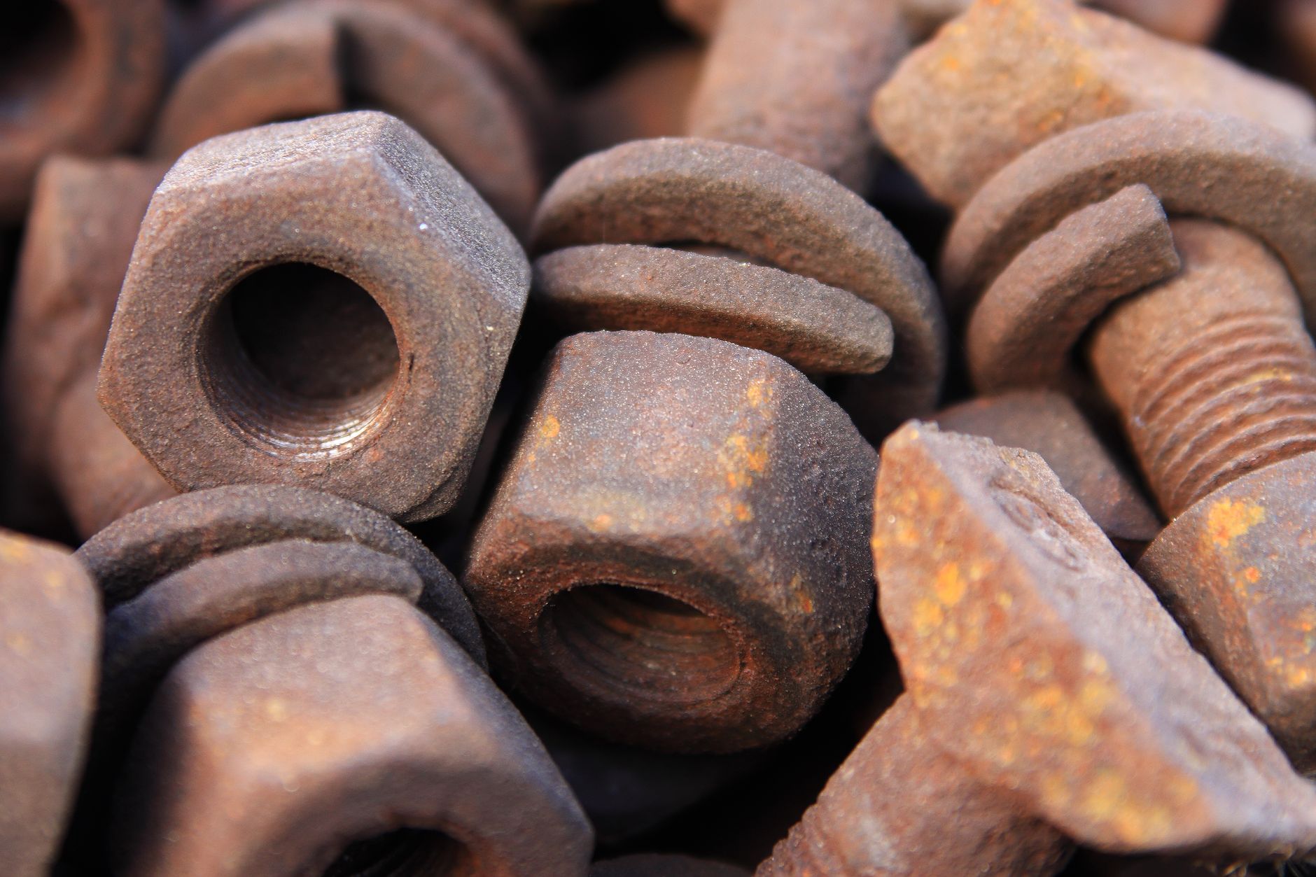 Close-up of a pile of rusty bolts and nuts showing detailed corrosion and texture.