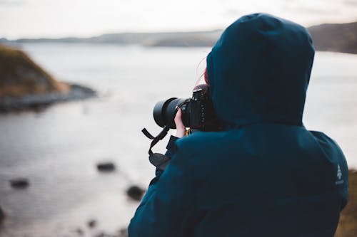 Unrecognizable female photographer with photo camera near ocean