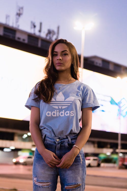 Trendy teen girl resting on illuminated street in evening Free