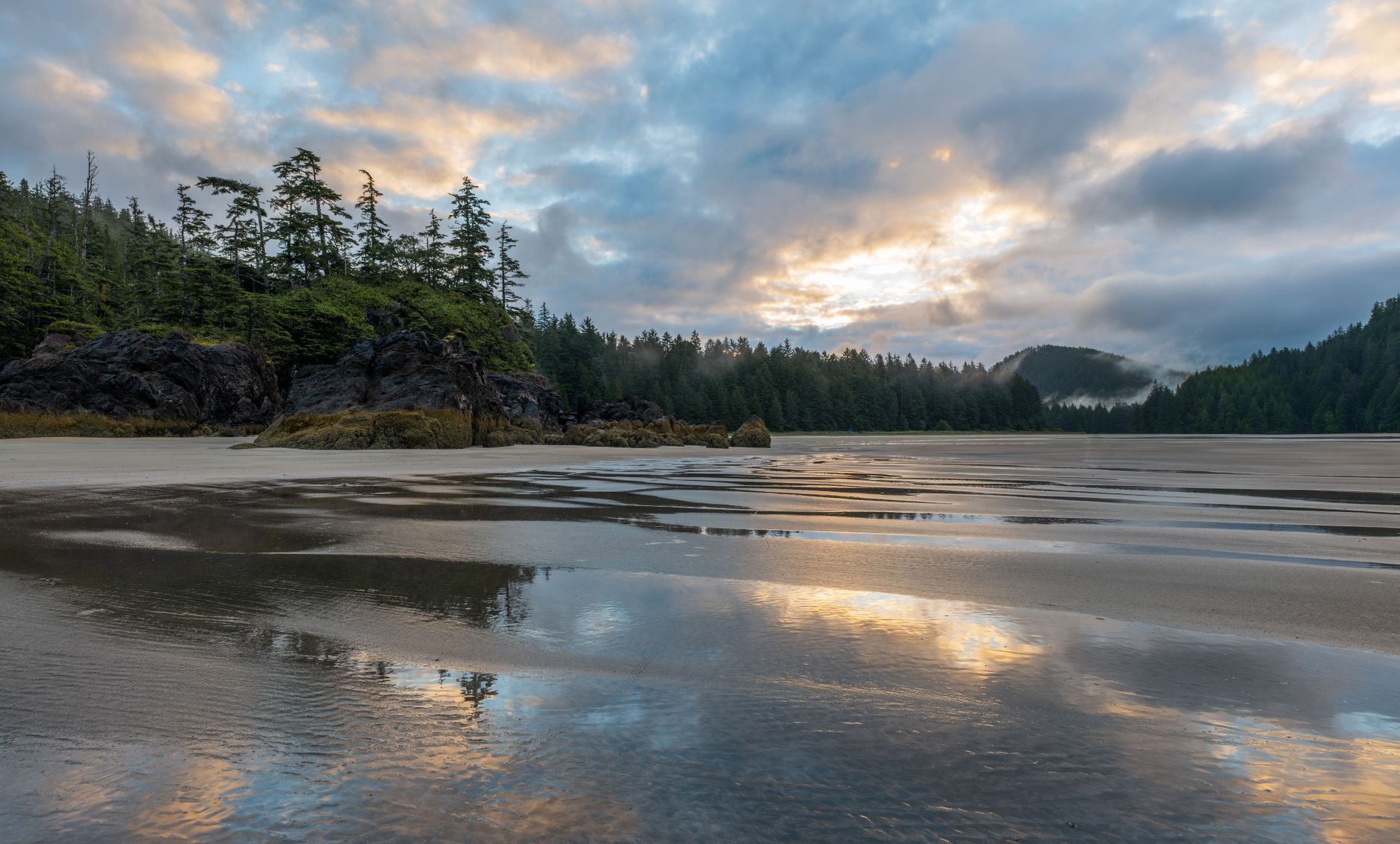 A captivating sunset view at San Josef Bay Beach, Canada, with reflective sands and lush trees.