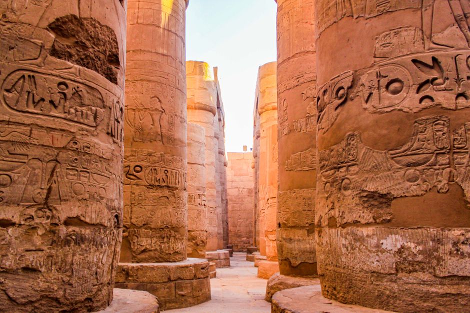 Karnak Temple Complex And Nile Cruise At Dusk Karnak Temple complex beside the Nile River, travelers walking through towering columns, dusk light, calm atmosphere, Luxor temple tour scene in Egypt