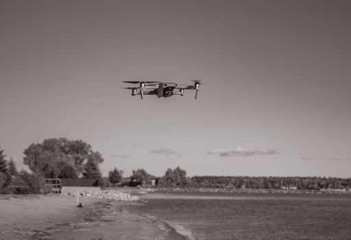 Black-and-white drone flying over a calm beach, capturing peaceful aerial views.