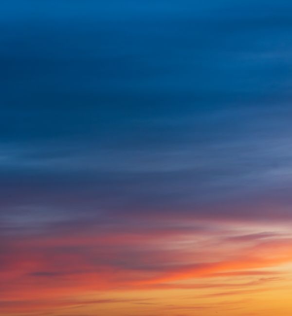 Céu de pôr do sol cativante com gradientes de cores vívidas, variando do azul ao laranja.