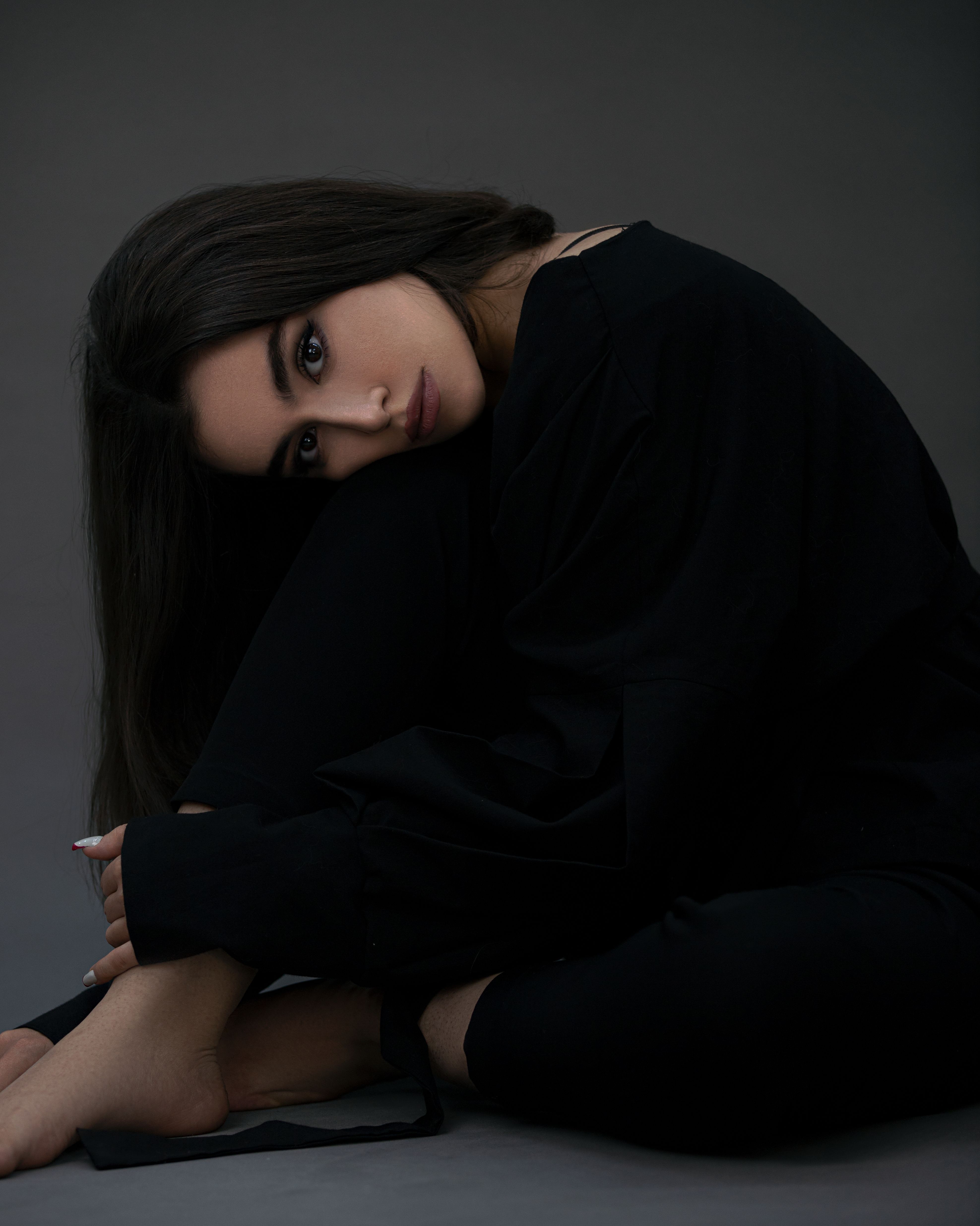Elegant portrait of a woman dressed in black, posing gracefully indoors.
