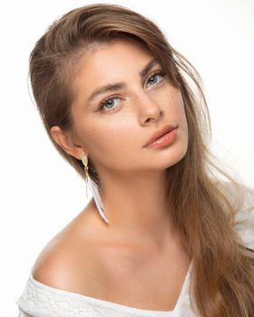 Stunning portrait of a woman with long hair and earrings against a white background.