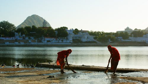 

People Sweeping beside a Lake