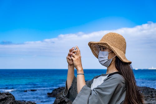 Free 
A Woman Wearing a Face Mask and a Hat Taking a Picture Stock Photo