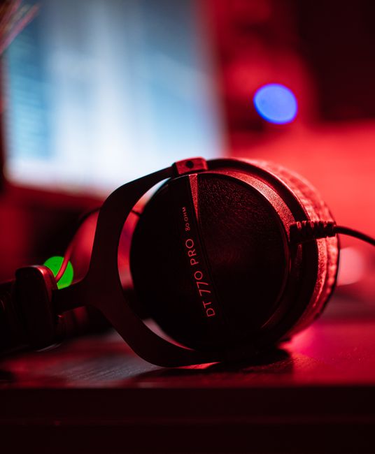 Detailed image of DT 770 PRO headphones on a desk, illuminated by red lighting, perfect for audio tech themes.