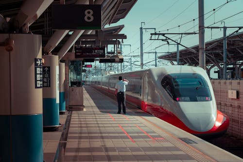 Anonymous man standing on railway station platform near contemporary train