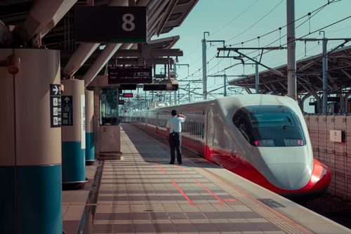 Free Back view of unrecognizable male worker standing on platform of railway station near modern high speed train on sunny day Stock Photo