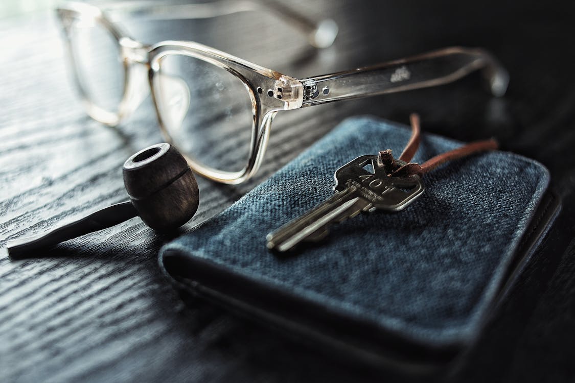 銀鑰匙在棕色煙斗和透明眼鏡旁邊的選擇性聚焦照片