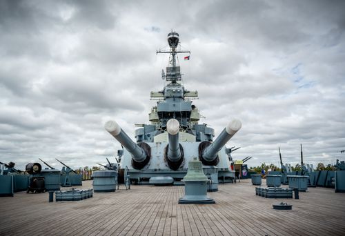 Free Front view of Battleship North Carolina with large naval guns against a cloudy sky in Wilmington. Stock Photo