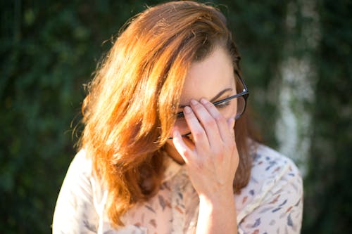 Femme Tenant Ses Lunettes En Position Assise