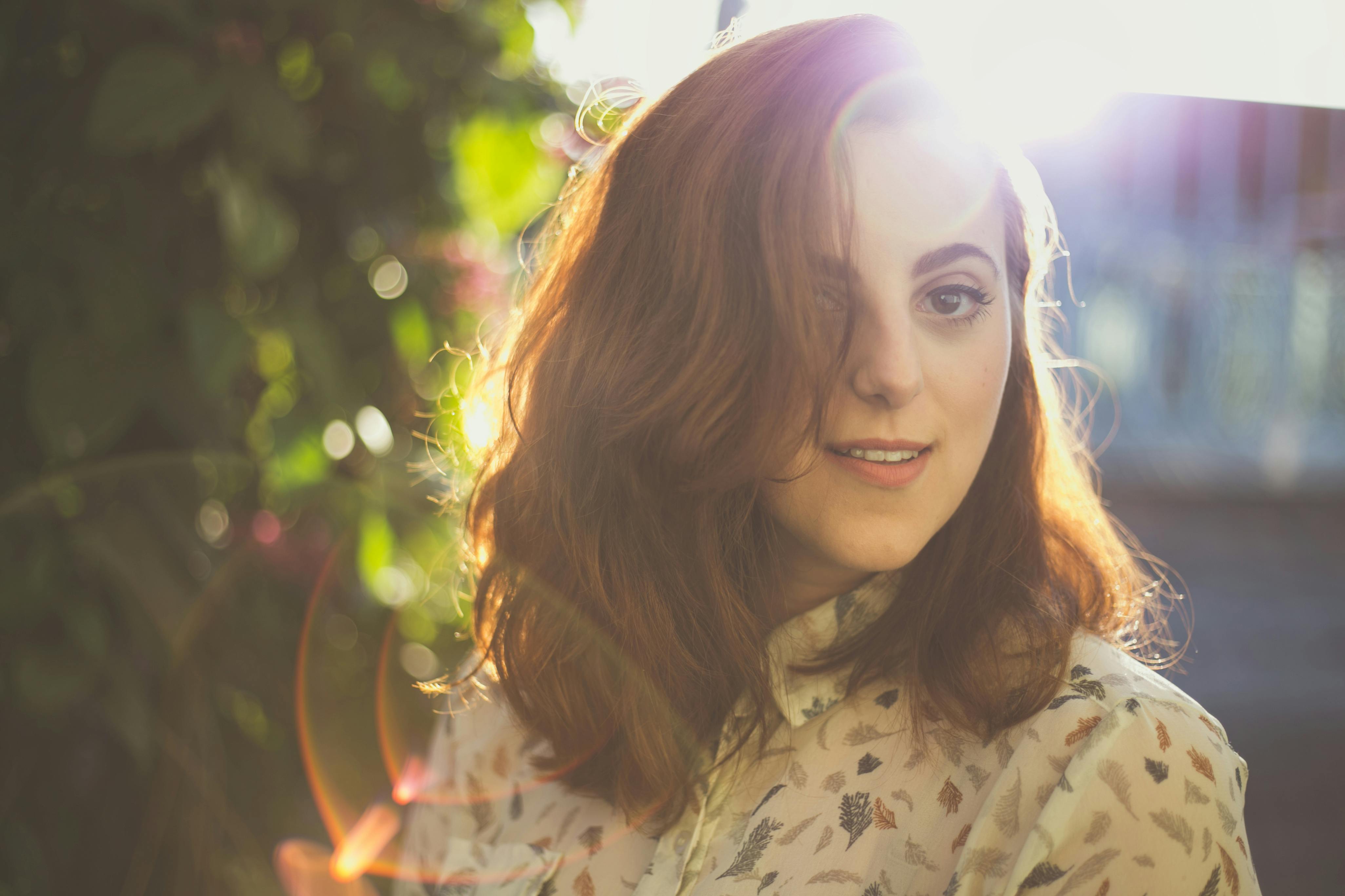 这幅年轻女子的肖像在阳光和散景中，捕捉了温暖自然的美