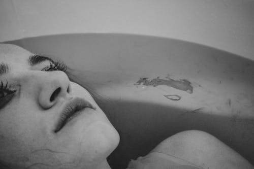 Emotionless woman in water of bathtub