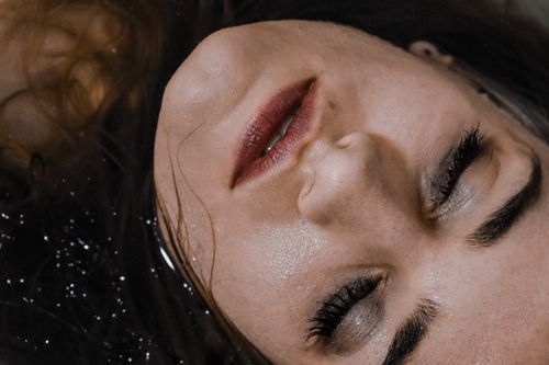 Free Top view of young female with eyeshadow and mascara relaxing in clean water Stock Photo