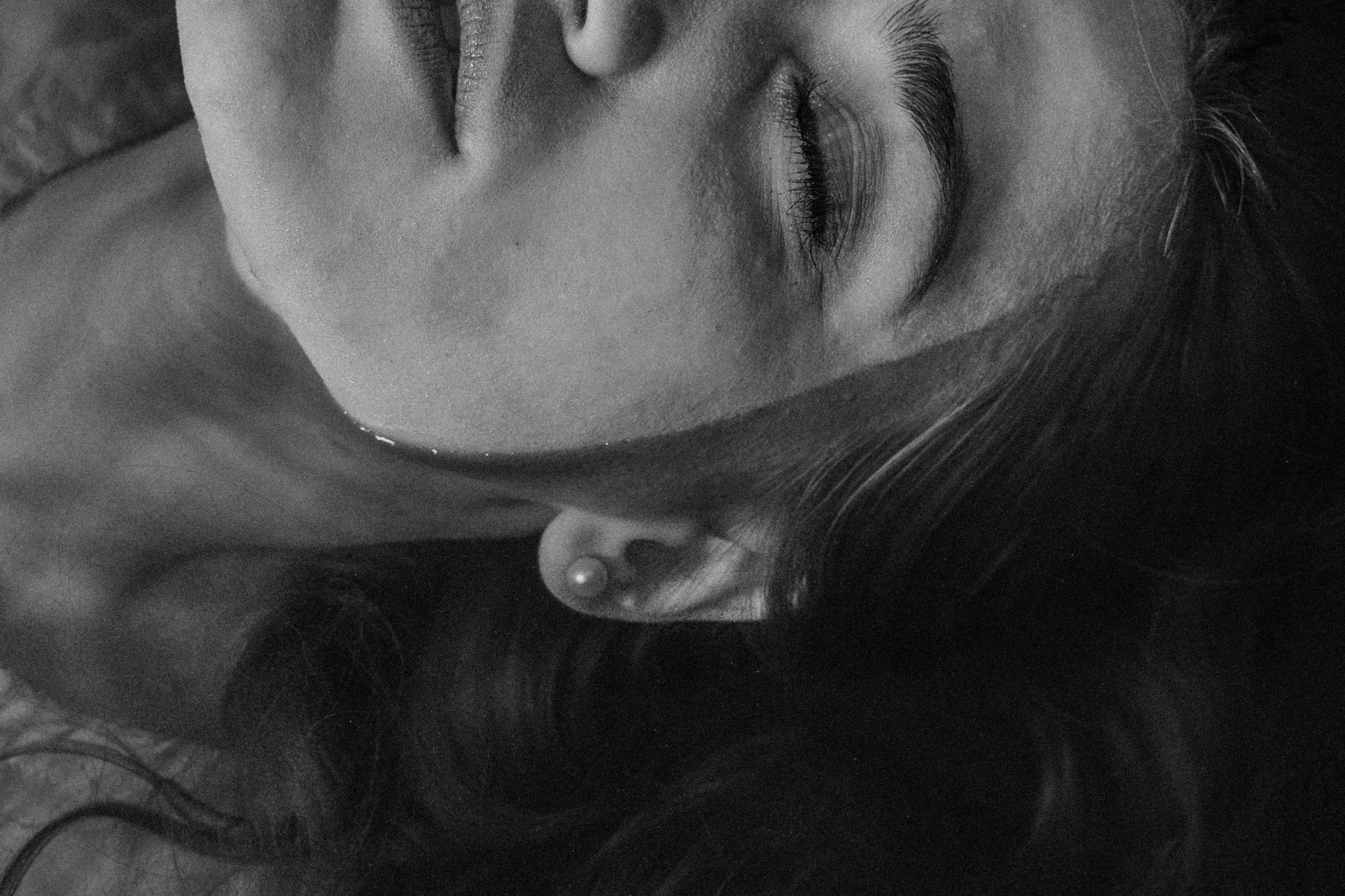 Black and white of relaxed female with closed eyes and shiny earrings in clean water