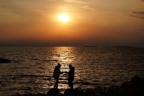 Free Silhouette of People Standing on Beach during Sunset Stock Photo