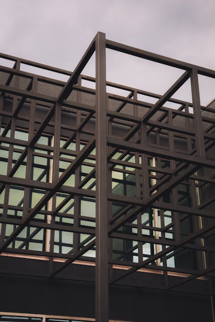 Low angle view of a modern steel framework with glass windows, emphasizing architectural design