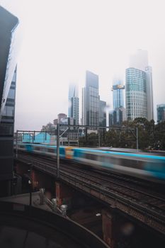 火车飞驰在摩天大楼林立的城市景观中，描绘出城市生活与交通的图景