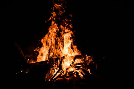 Mesmerizing campfire flames burning brightly against a dark night backdrop.