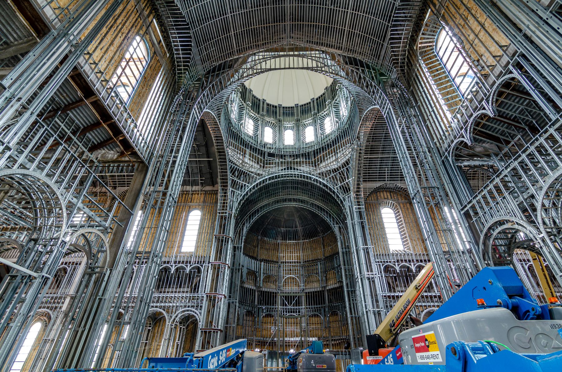 Low-angle view of scaffolding and exposed steel framing inside a building under construction.