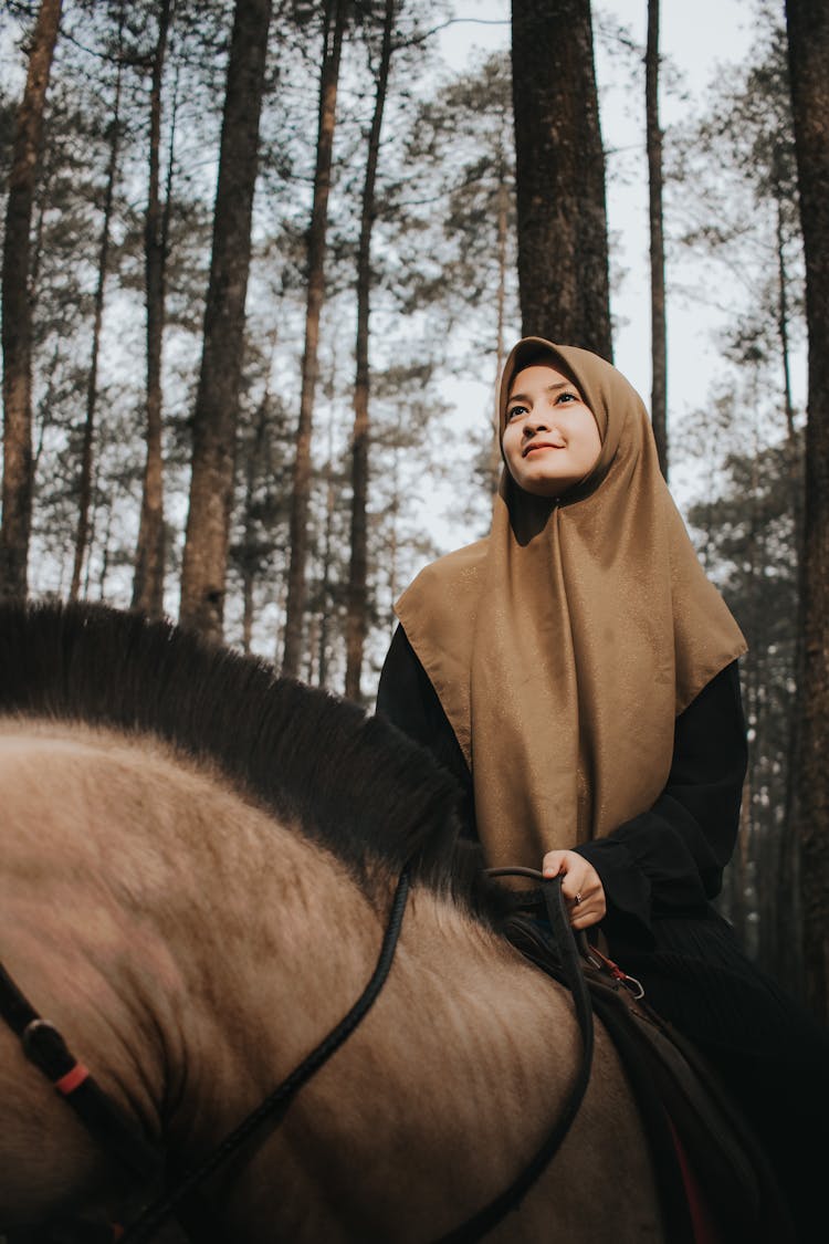 Positive Muslim Woman Riding Horse In Forest