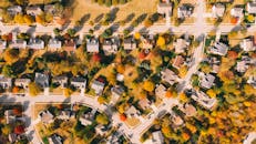 Building roofs between bright autumn trees and roadways