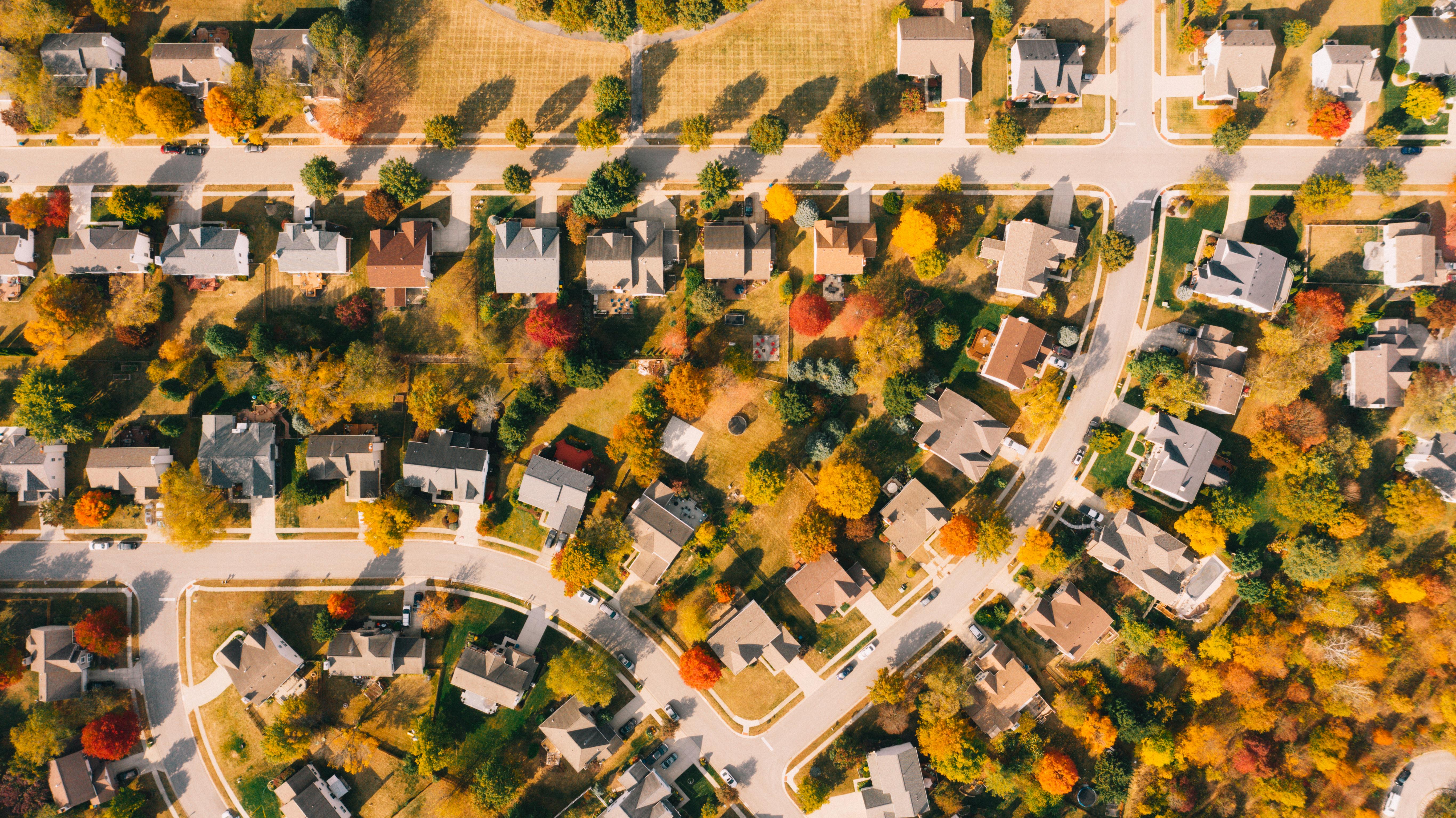 Building roofs between bright autumn trees and roadways