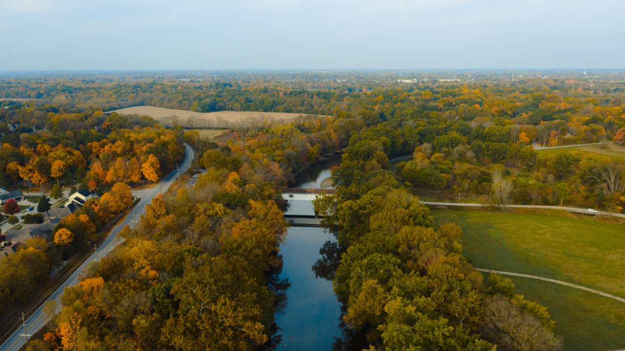 aerial view of bridge above river between roadway and lush woods near