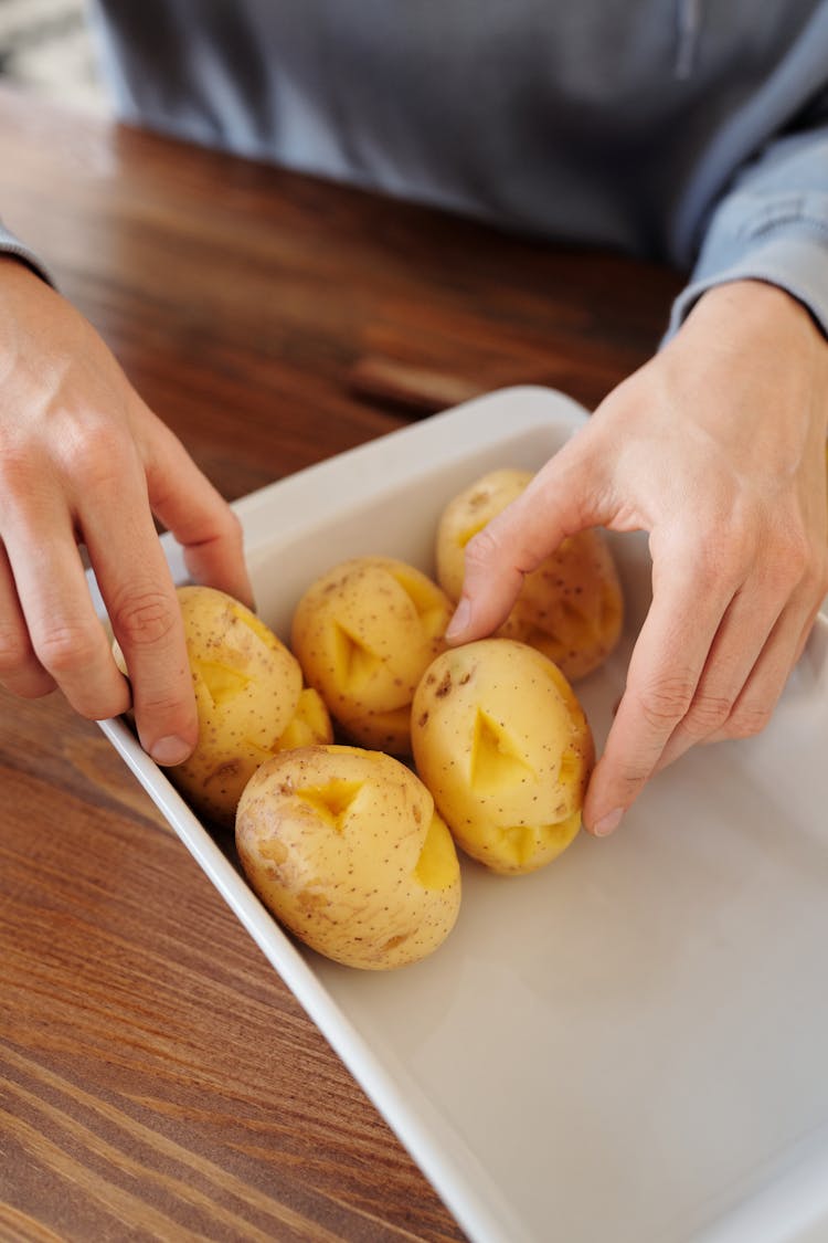 Person Holding A White Tray With Potatoes