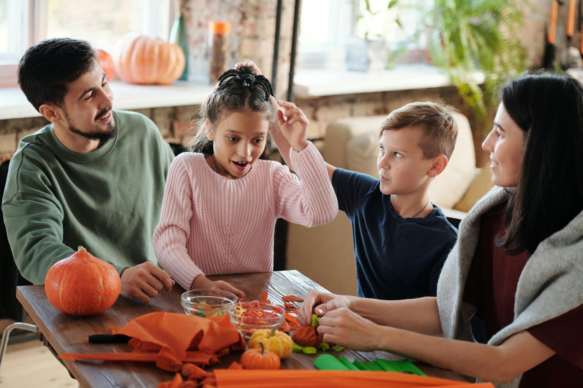 A joyful family crafting Halloween decorations together with pumpkins indoors.