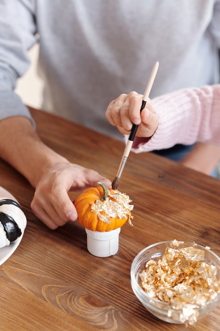 Father And Daughter Decorating A Pumpkin