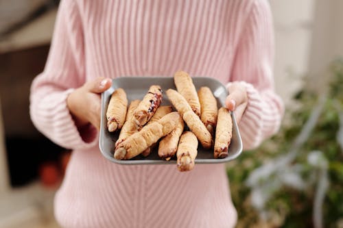 Person Holding A Tray Of Bread With Witch Fingers Design 