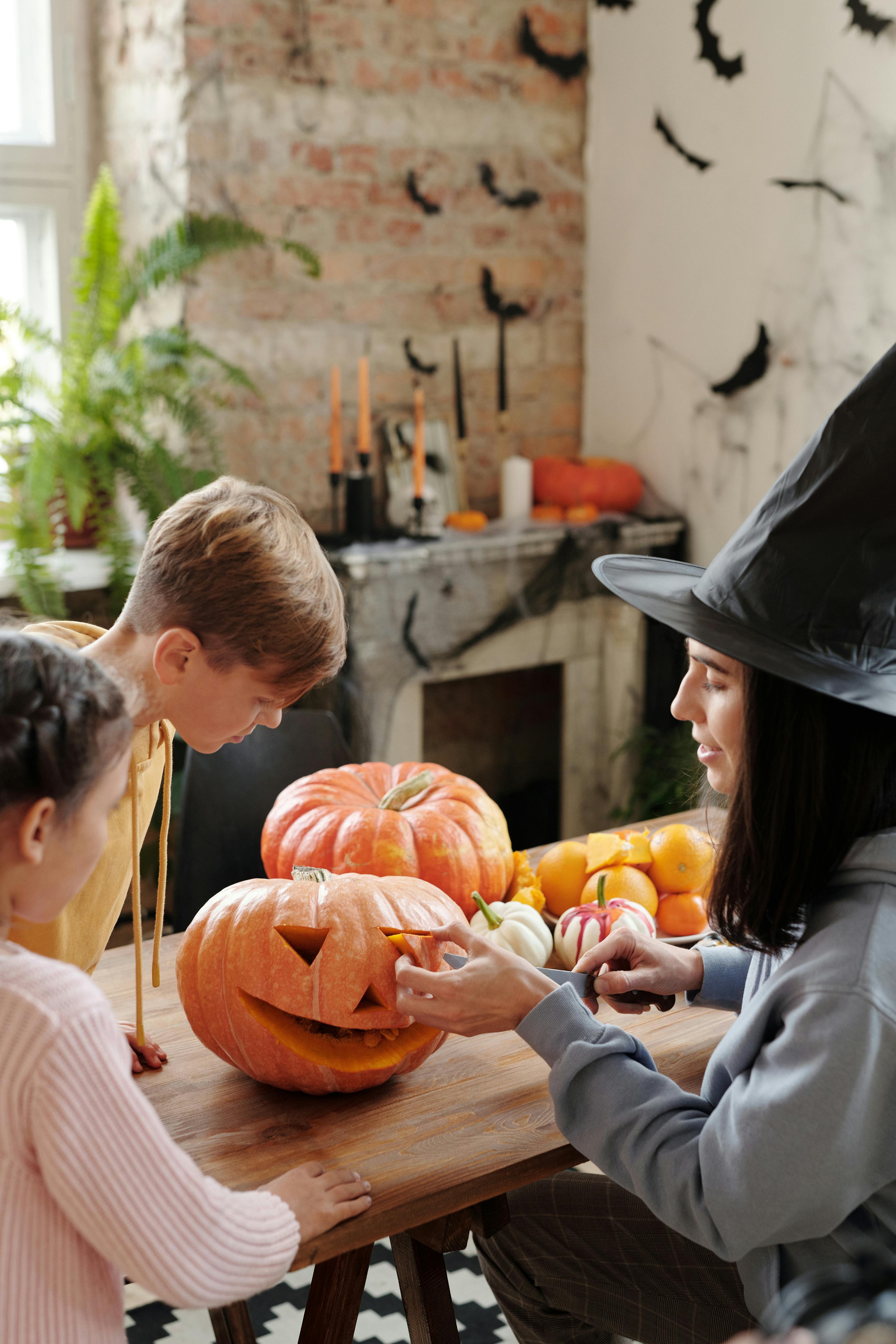 a mother carving a pumpkin while the children are watching