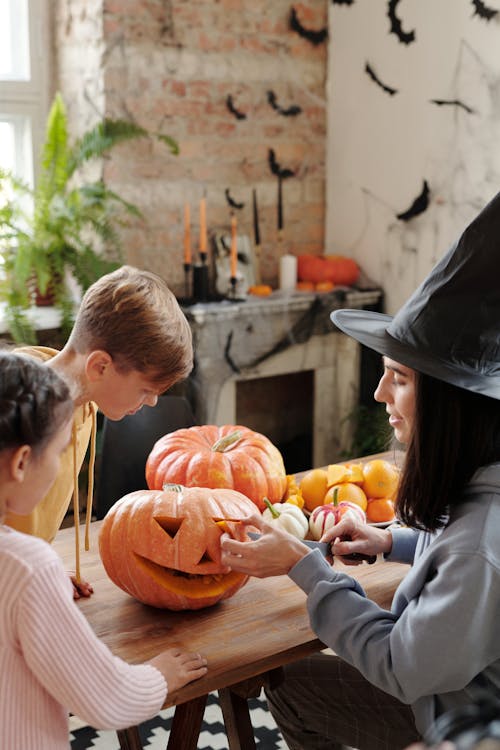 A Mother Carving A Pumpkin While The Children Are Watching