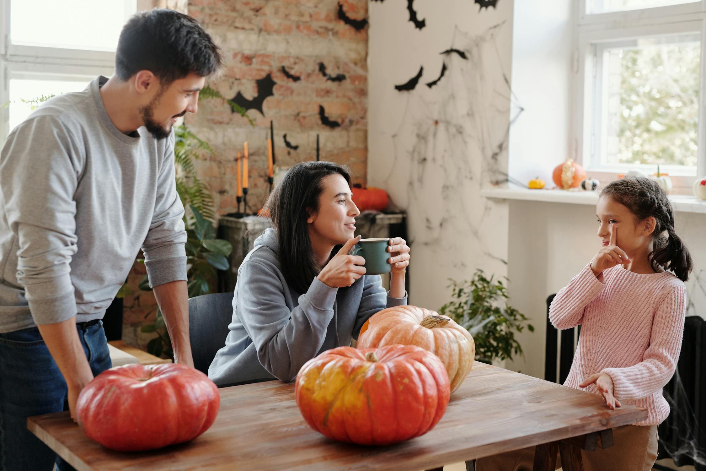 A family sat around a table filled with pumpkins and with Halloween decorations up in the background.