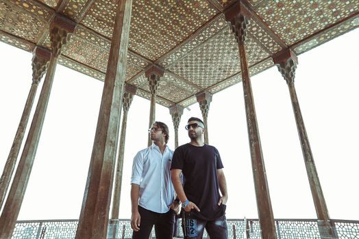 Two men under ornate pavilion in Isfahan with traditional architecture.