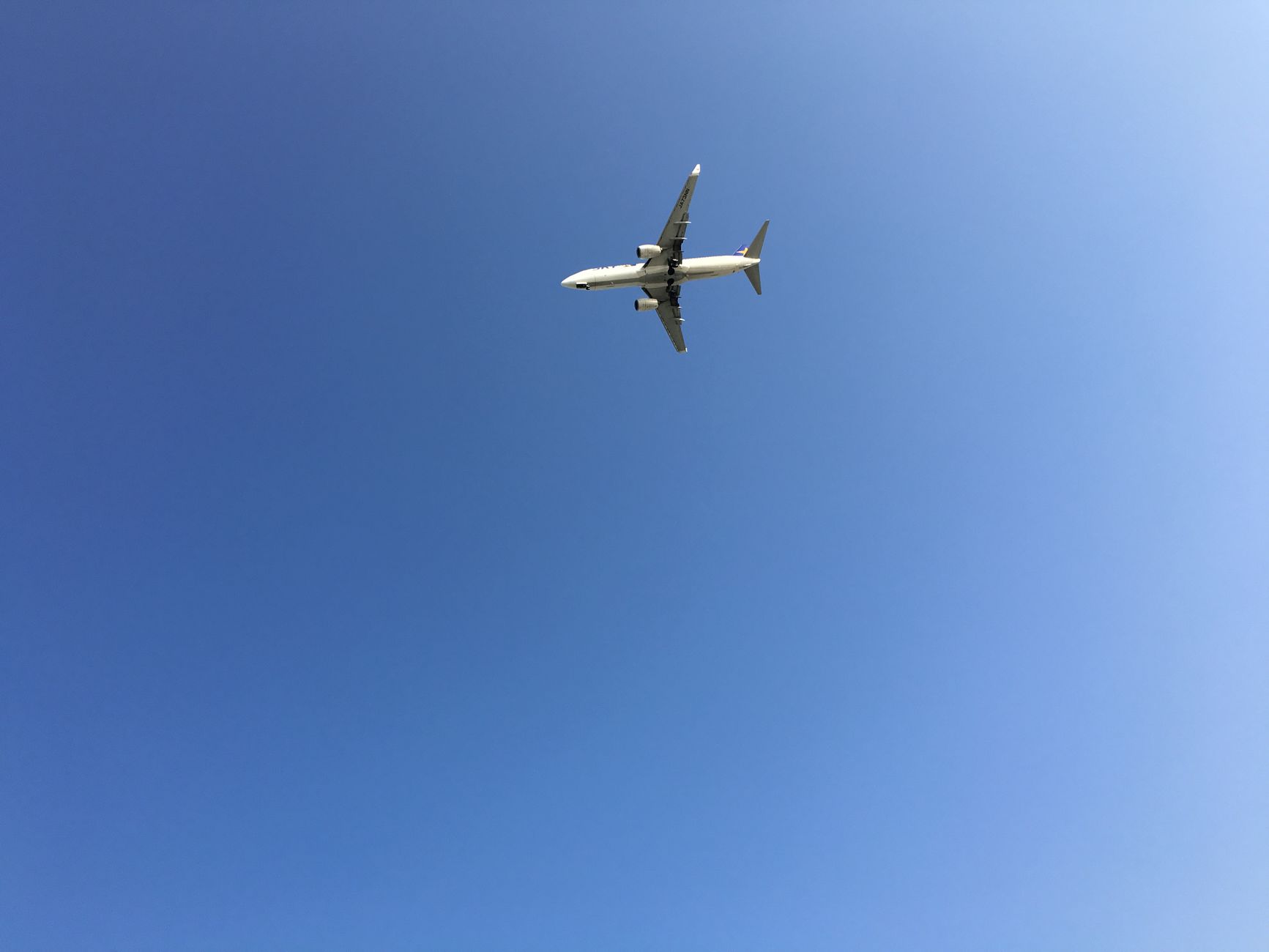 A commercial airplane flying high against a vibrant clear blue sky, showcasing aviation and travel.