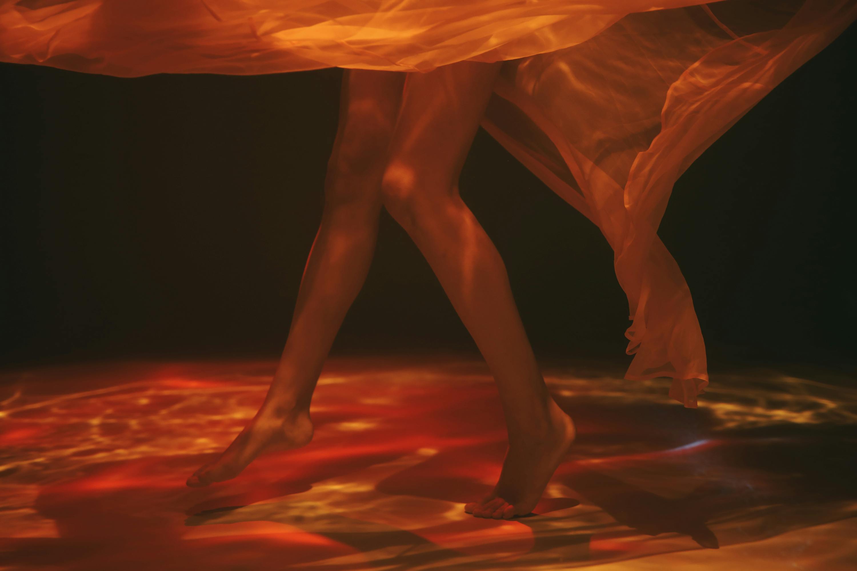 这张水下照片富有创意，拍摄了腿部与透明面料，呈现出一种喜怒无常、空灵的感觉