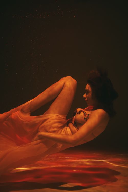 Free Surreal shot of a woman submerged underwater in flowing fabric, creating a dreamy aesthetic. Stock Photo