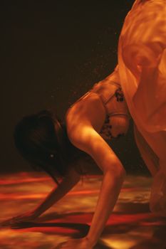 这幅画以橙色色调描绘了一名女子在水下优雅移动的场景