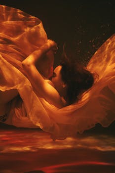 A woman floats gracefully underwater with flowing fabric, creating an ethereal and artistic scene.