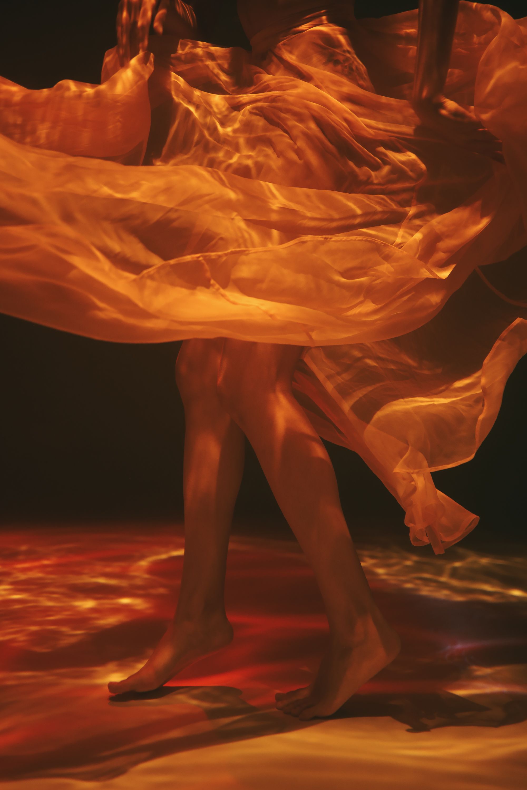 Captivating artistic shot of a dancer with swirling sheer fabric captured in warm lighting.