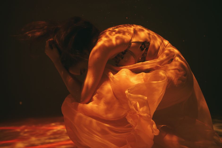 Ethereal underwater image of a woman in flowing dress, exuding a sense of calm and mystery.
