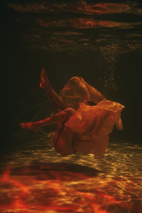 Woman in Sheer Dress submerged underwater 