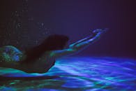 一个宁静的女人在水下游泳，被空灵的光和气泡包围