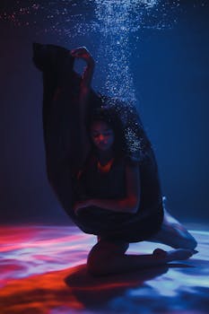 一位优雅的模特笼罩在迷人的灯光中，在水下摆出姿势，营造出空灵而艺术的场景