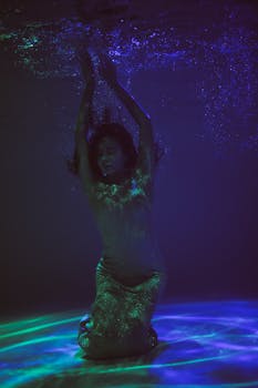 这张水下照片引人入胜，一位女士优雅地摆出姿势，散发着神秘而空灵的氛围