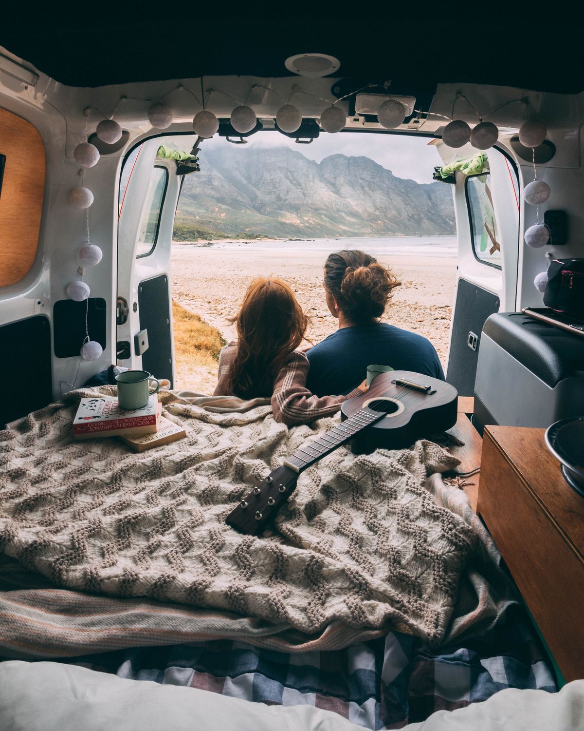Couple relaxing on the roof of a campervan overlooking the landscape